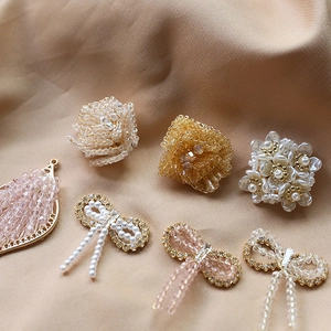 Makroaufnahme von handgefertigten Perlenblumen, Kristallbögen und Tropfenanhängern für DIY-Schmuck