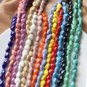 Detailed view of colorful heart-shaped ceramic beads for DIY jewelry on a white porcelain plate