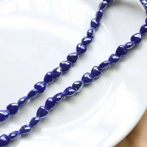 Macro detail of glossy dark blue heart ceramic beads for DIY jewelry making and crafts