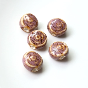 Macro shot of 5 handmade ceramic beads with purple swirl glaze and center holes