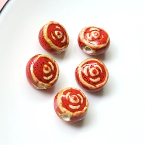 Detailed macro view of five vintage red floral pattern handmade ceramic beads