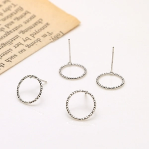 Detail of four silver hoop earrings with twisted rope texture on vintage paper