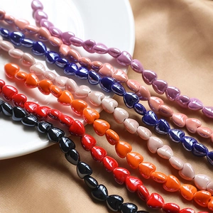 Colorful 3D heart ceramic beads for DIY jewelry making displayed on elegant satin fabric