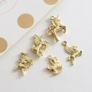 Detailed view of five unique gold-plated alloy unicorn and horse charms for DIY jewelry making