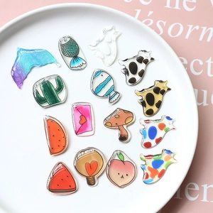 Flat lay of translucent acrylic charms with cat, fish, and watermelon patterns for DIY
