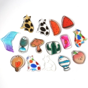 Flat lay of translucent acrylic charms in cat, fish, and fruit shapes for DIY jewelry