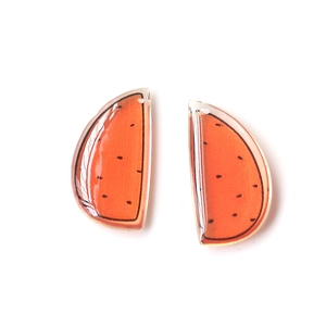 Close-up of translucent orange acrylic watermelon charms with pre-drilled holes for DIY jewelry