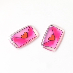 Close-up of translucent acrylic pink envelope charms with red heart for DIY jewelry making