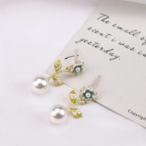 Dettaglio degli orecchini a fiore con perle, smalto verde e placcatura in oro