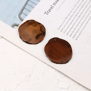 Close-up of irregular resin earrings with deep brown amber texture and marble pattern