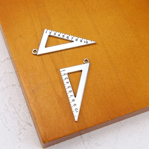 Detailed view of silver triangular ruler charms with scale marks for DIY jewelry making