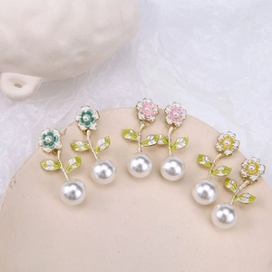 Orecchini a fiore con perle nei colori verde, rosa e giallo su piatto in ceramica