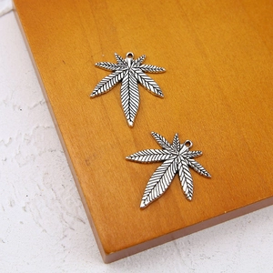 Detailed view of two vintage silver leaf alloy pendants with intricate vein patterns