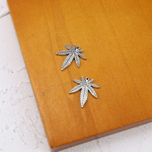 Detailed close-up of two silver hemp leaf pendants with intricate vein patterns for DIY