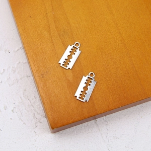 Silver razor blade charms for DIY jewelry making, close-up on wooden display stand