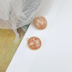 Detailed macro view of coral pink resin pendants with gold serrated edges for DIY jewelry