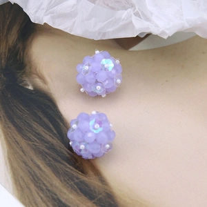 Close-up of handmade purple beaded ball earrings with iridescent petal sequins