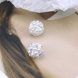 Close-up of handmade white pearl ball earrings with iridescent AB sequins on a white background