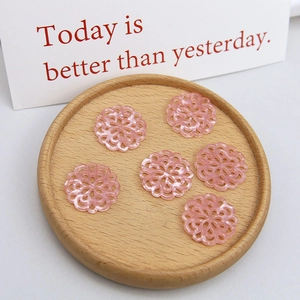 Detail of pink resin floral hollow pendants on a wooden tray for DIY jewelry