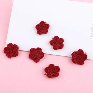 Detail van zes handgemaakte bordeauxrode gehaakte bloemen voor DIY haarspeldjes