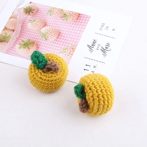 Detail of two handmade yellow knitted fruits with green leaves for DIY craft accessories
