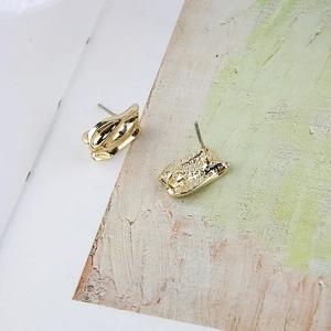Detalle de pendientes geométricos dorados irregulares con acabado de metal líquido pulido