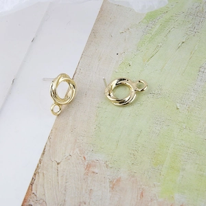 Primer plano de aretes DIY de círculo dorado retorcido con bucles y pasadores de plata