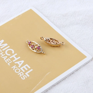 Macro detail of 18K gold plated leaf-shaped jewelry connectors with red zircon stones