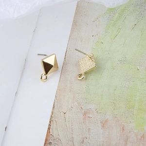 Detalle de pendientes de pirámide dorados con lazo para colgar joyería DIY