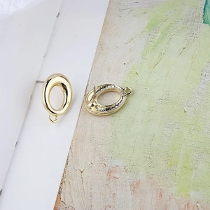 Primer plano de aretes ovalados dorados con bucle para creación de joyas artesanales
