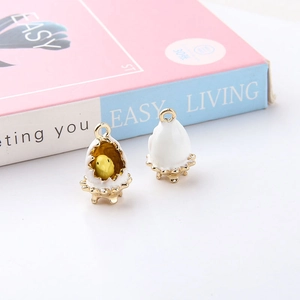 Detail showing gold alloy chicken and egg shell enamel charms on a minimalist background