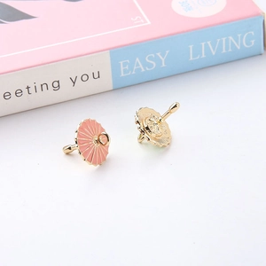 Close-up of mini pink enamel umbrella pendants for DIY jewelry making and earring crafts