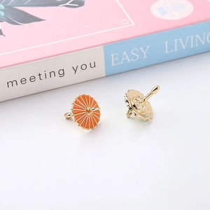 Detail view of mini umbrella charms with orange enamel and golden metal alloy finish