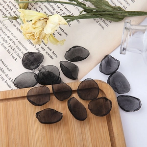 Detail view of black mesh flower petals for DIY jewelry making on vintage book background