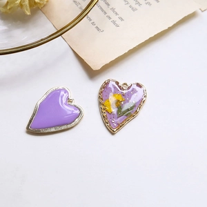 Dettagli di ciondoli a cuore con smalto viola, foglia d'oro e fiori secchi per gioielli