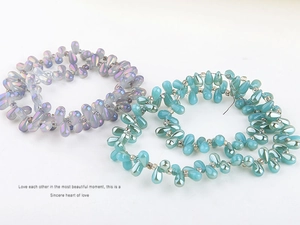Macro detail of colorful teardrop glass beads in light purple and teal for DIY jewelry