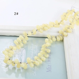 Detailed view of light yellow teardrop glass beads with silver spacers for DIY jewelry making