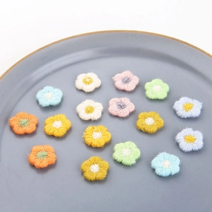 Handgemaakte gehaakte bloemaccessoires in pastelkleuren op een keramisch bord