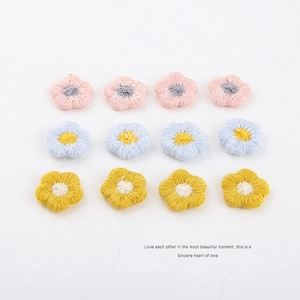 Platte weergave van 12 handgemaakte gehaakte bloemen in roze, blauw en geel voor DIY-sieraden