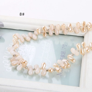 Macro detail of pearlescent teardrop beads in light beige on a decorative white frame