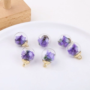 Detail view of six glass bubble pendants filled with real purple dried flowers and gold caps