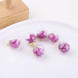 Detail of six glass bubble charms with purple dried flowers and gold metal caps for DIY jewelry