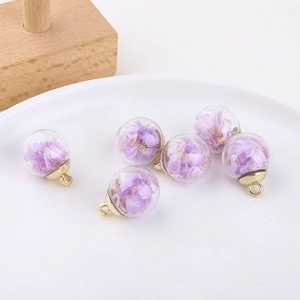 Detail of round glass bubble pendants with purple dried flowers and gold metal hooks