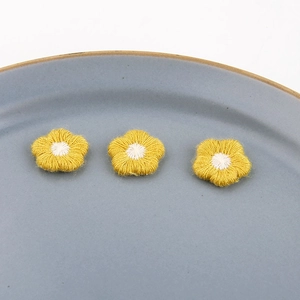 Macro-opname van drie gele geborduurde bloemen voor DIY-sieraden en haaraccessoires