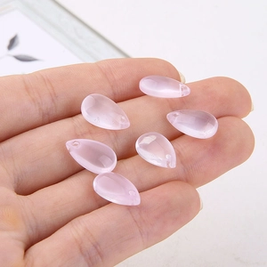 Macro detail of six pink glass teardrop beads held in hand for DIY jewelry making