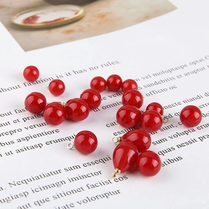 Macro shot of glossy red round and teardrop pearl charms for DIY jewelry making