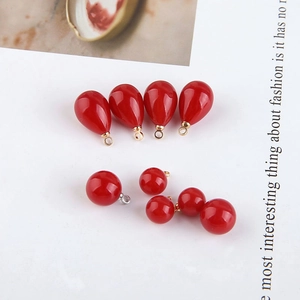 Macro shot of red waterdrop and round pearl pendants with metal rings for DIY jewelry