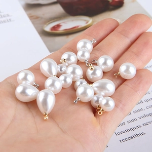 Detail of drop-shaped faux pearl pendants with gold hooks for DIY jewelry making