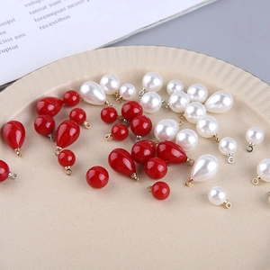 Close-up of red and cream faux pearl charms in teardrop and round shapes for DIY jewelry