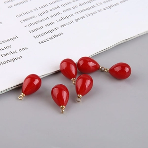 Macro detail of five red teardrop charms with gold loops for DIY jewelry making